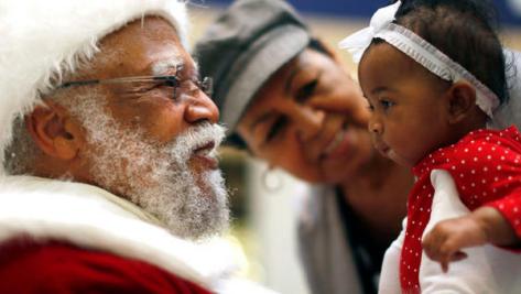 African American Santa Claus Langston Patterson (L), 77, greets four-month-old Raelyn Price as her grandmother Gloria Boissiere looks on, at Baldwin Hills Crenshaw Plaza mall in Los Angeles, California, December 16, 2013. Patterson has worked as Santa since 2004 at the mall, which is one of the few in the country with a black Santa Claus. (REUTERS/Lucy Nicholson)